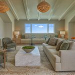 This is a photo of The Seville's assisted living community room, featuring doors that lead to the outdoor community room terrace, comfortable seating, and a large TV.